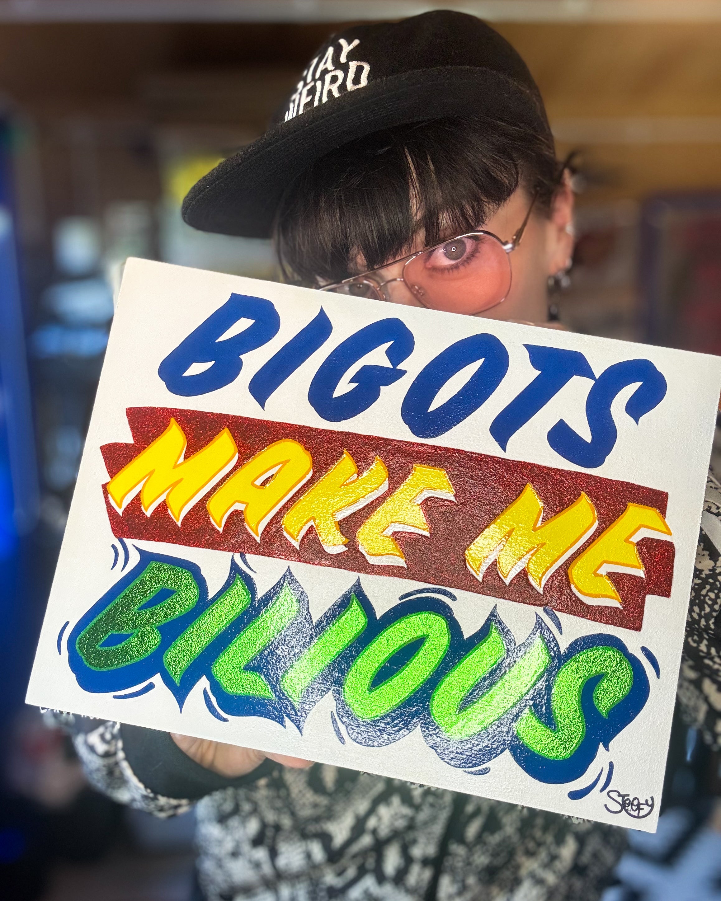 Stoofy aka Shiv Mac holding up original Stoofy sign-writing artwork from contemporary art collection 'Primary Concerns' collection - Bigots Make Me Bilious