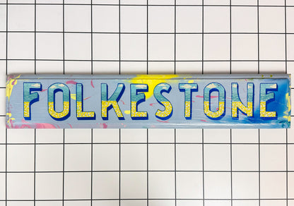Hand-painted "Folkestone" wooden sign in vibrant colours – a bold tribute to the Kent coast. Original wall art with vintage charm and Stoofy character.
