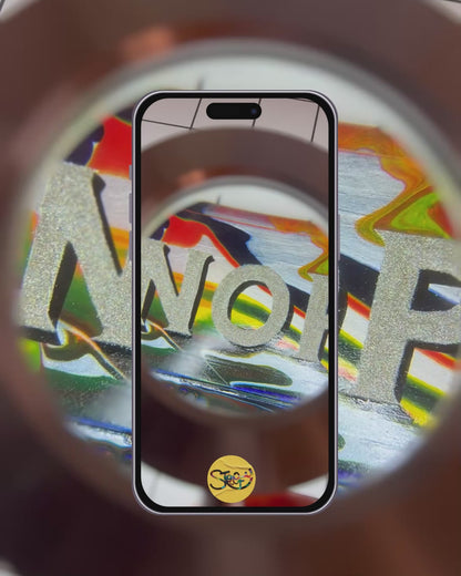 Hand-painted 'NOPE TO TAUPE' sign being looked at underneath a magnifying glass, highlighting yhr bold, colourful, glittery lettering, background and shiny gloss finish.